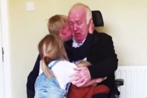 Drei Kinder umarmen ihren Großvater