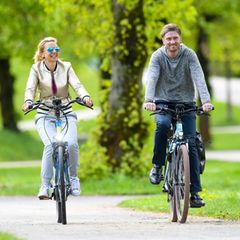 Ein Paar fährt auf E-Bikes durch einen Park