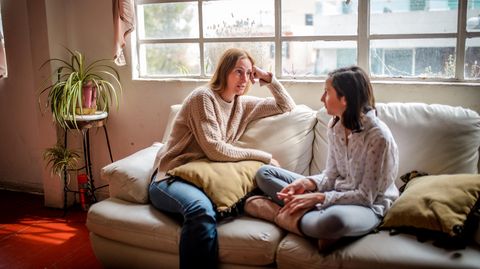 Mutter und Tochter sitzen auf der Couch und unterhalten sich