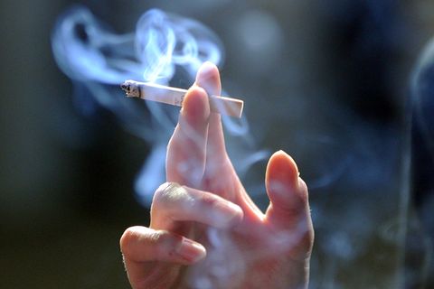 Eine Hand hält eine qualmende Zigarette