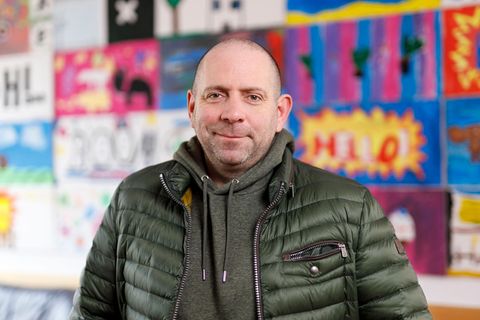 Matthias Distel aka Ikke Hüftgold steht vor einer bunten Wand