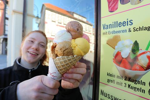 Ein junges Mädchen hält eine Tüte Eis mit mehreren bunten Eiskugeln
