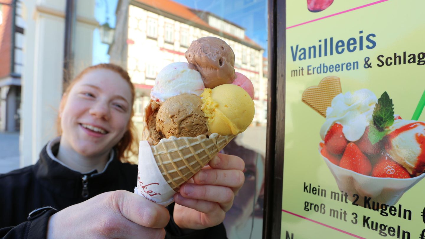 Ein junges Mädchen hält eine Tüte Eis mit mehreren bunten Eiskugeln