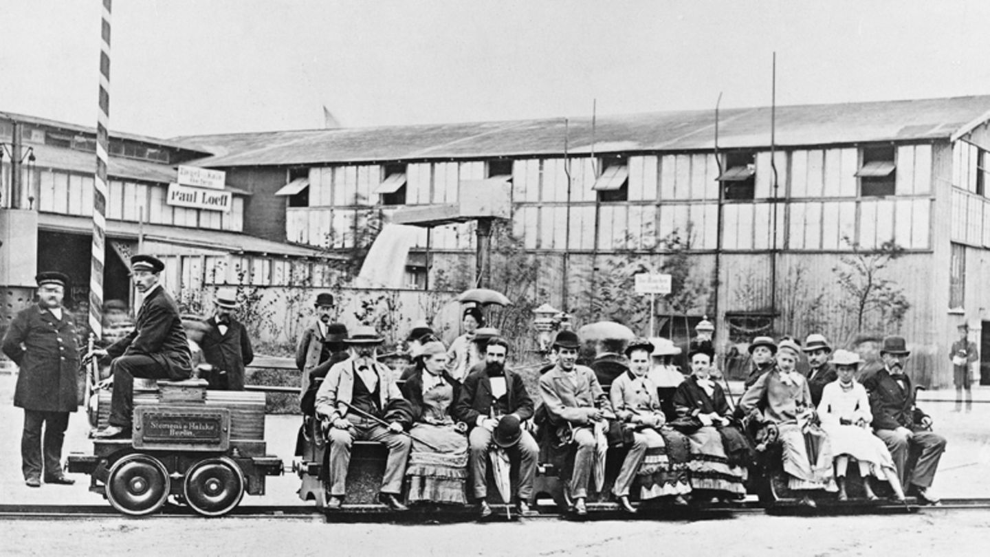 Bilder der Weltgeschichte: 31. Mai 1879: Werner Siemens führt erste praxistaugliche Elektrolok vor Groß war die Maschine nicht, und ihr Weg war kurz, dennoch hat die Fahrt der kleinen Elektrolok auf einem nur 300 Meter langen Rundkurs auf der Berliner Gewerbeausstellung am 31. Mai 1879 eine neue Ära eingeläutet. Die bei Siemens und Halske entwickelte Lokomotive bewies, dass sie eine größere Anzahl von Personen transportieren konnte und erwies sich damit als erstes Exemplar als praxistauglich. Wenn man so will ein früher Meilenstein der E-Mobilität. Werner Siemens, später "von Siemens", präsentierte seine Entwicklung mit Stolz. Der Industrielle ist bekannt als Begründer der modernen Elektrotechnik und Entdecker des elektrodynamischen Prinzips, der Grundlage für elektrische Generatoren. 31. Mai 1879: Werner Siemens führt erste praxistaugliche Elektrolok vor Groß war die Maschine nicht, und ihr Weg war kurz, dennoch hat die Fahrt der kleinen Elektrolok auf einem nur 300 Meter langen Rundkurs auf der Berliner Gewerbeausstellung am 31. Mai 1879 eine neue Ära eingeläutet. Die bei Siemens und Halske entwickelte Lokomotive bewies, dass sie eine größere Anzahl von Personen transportieren konnte und erwies sich damit als erstes Exemplar als praxistauglich. Wenn man so will ein früher Meilenstein der E-Mobilität. Werner Siemens, später "von Siemens", präsentierte seine Entwicklung mit Stolz. Der Industrielle ist bekannt als Begründer der modernen Elektrotechnik und Entdecker des elektrodynamischen Prinzips, der Grundlage für elektrische Generatoren.
