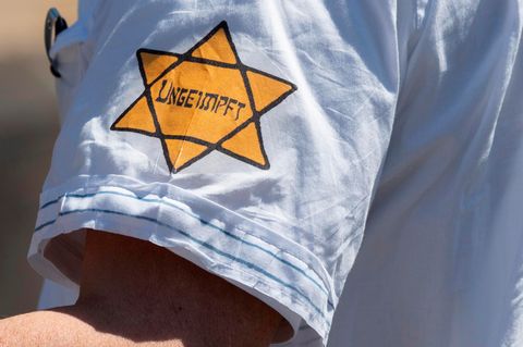 "Ungeimpft" steht auf einem nachgebildeten Judenstern am Arm eines Mannes auf einer Demonstration in Frankfurt am Main
