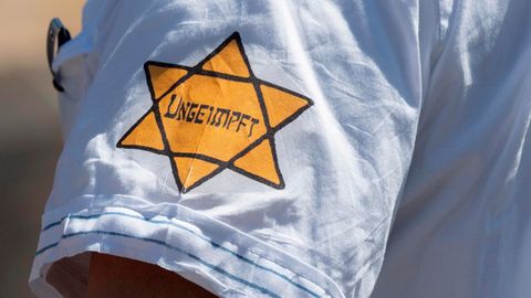 "Ungeimpft" steht auf einem nachgebildeten Judenstern am Arm eines Mannes auf einer Demonstration in Frankfurt am Main