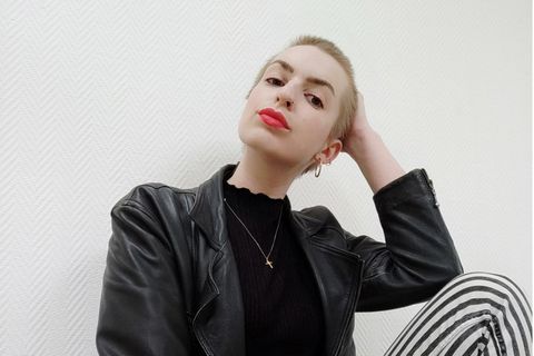 Maike Schöfer sitzt in Lederjacke vor einer weißen Wand