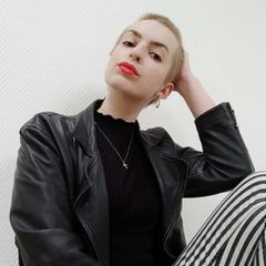 Maike Schöfer sitzt in Lederjacke vor einer weißen Wand