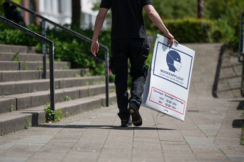 Mann trägt Maskenpflicht-Schild