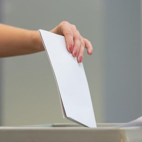 Eine Frau wirft ihren Stimmzettel in eine Wahlurne