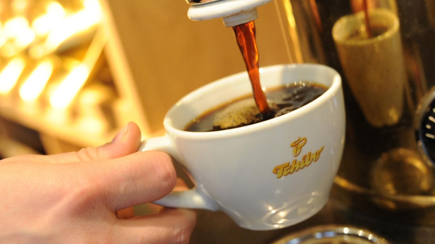 Ein Tchibo-Mitarbeiter füllt eine Kaffeetasse