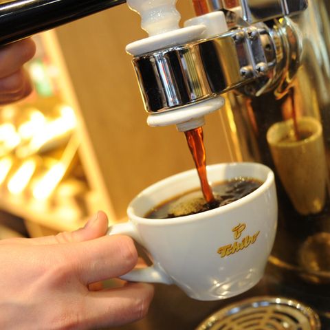 A Tchibo employee fills a coffee cup