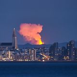 Fagradalsfjall auf Island  Dieses Foto, mit einem starken Teleobjektiv aufgenommen, zeigt die Skyline der Hauptstadt Reykjavik mit dem 32 Kilometer entfernten feuerspeienden Vulkan im Hintergrund.