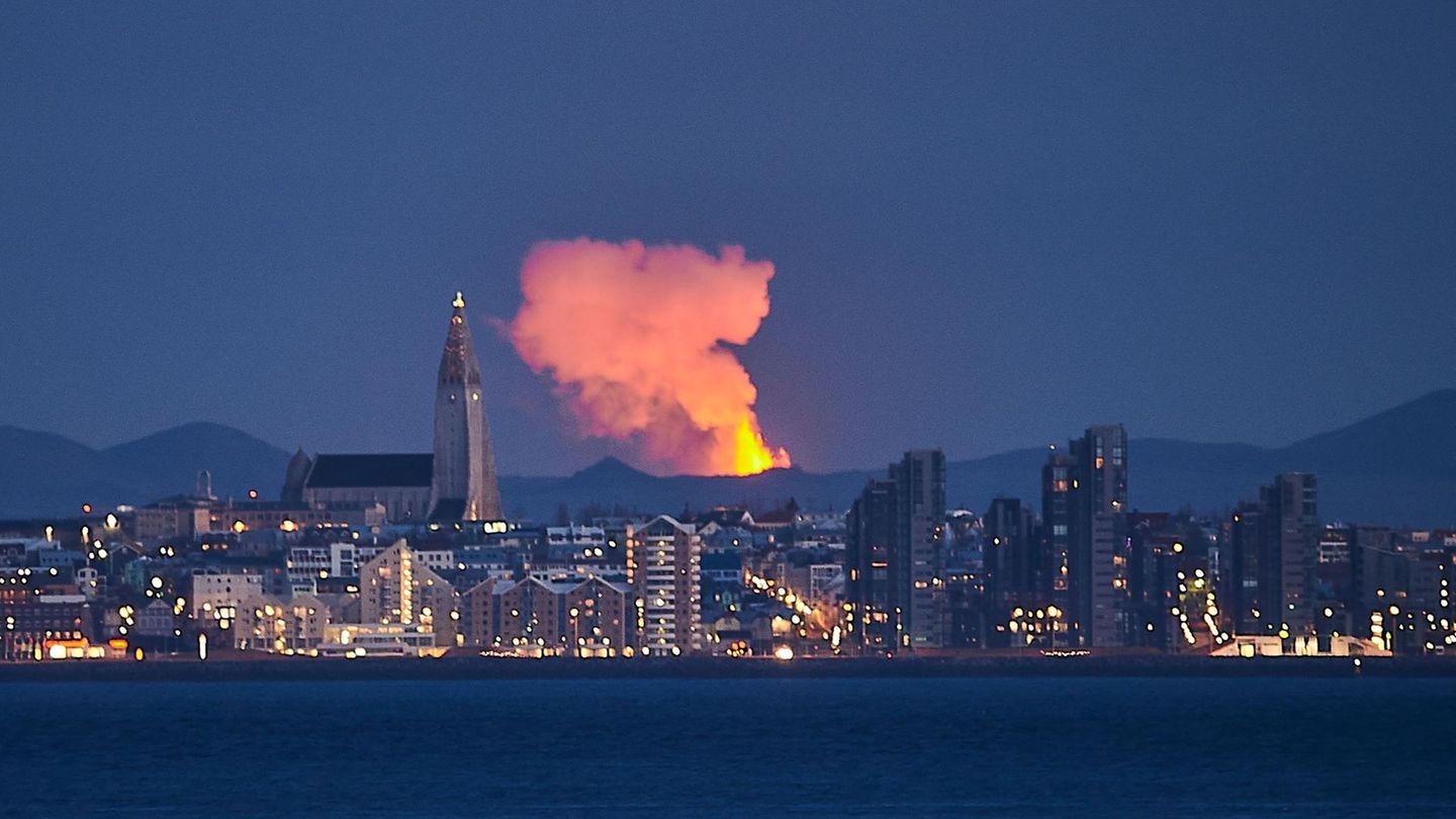 Fagradalsfjall auf Island  Dieses Foto, mit einem starken Teleobjektiv aufgenommen, zeigt die Skyline der Hauptstadt Reykjavik mit dem 32 Kilometer entfernten feuerspeienden Vulkan im Hintergrund.