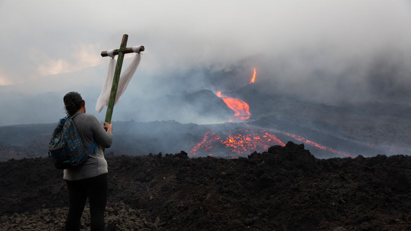 Pacaya in Guatemala  Ortswechsel nach Mittelamerika, wo der Pacaya seit Anfang Februar wieder aktiv ist. Eine Frau trägt während einer Pilgerfahrt im Mai ein Holzkreuz und betet, damit sich die Eruptionen in Grenzen halten.