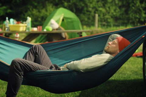 Outdoor Hängematte: Junger Mann schläft auf einem Zeltplatz in der Hängematte