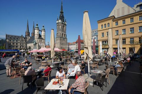 Gäste sitzen in einem geöffneten Freisitz bei frühsommerlichen Temperaturen und Sonnenschein
