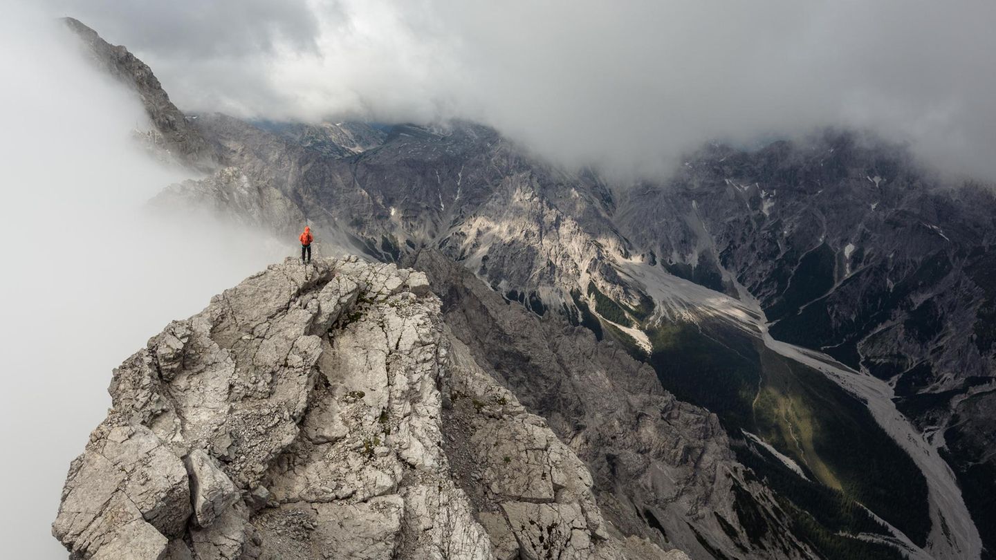 Die Mittelspitze ist mit 2713 Metern der höchste der drei Watzmanngipfel. Sie blitzt aus den Wolken hervor, während rechts unten sich durchs Wimbachtal mächtige Schuttströme aus Gestein ziehen.