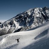 Watzmann im Winter: Ein Snowboader fährt über die tiefverschneiten Hänge der Hochalm. Gegenüber sind die Westwände des Watzmannstocks zu sehen.