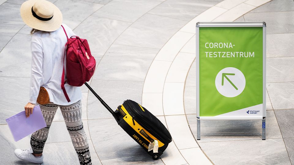 Teuerer Urlaub: Kosten für notwendigen PCR-Test sorgen für Verärgerung Frau mit Koffer geht zu einem Corona-Testzentrum
