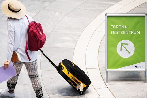 Frau mit Koffer geht zu einem Corona-Testzentrum