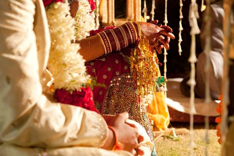 Die Hände eines indischen Paars in Hochzeitskleidung