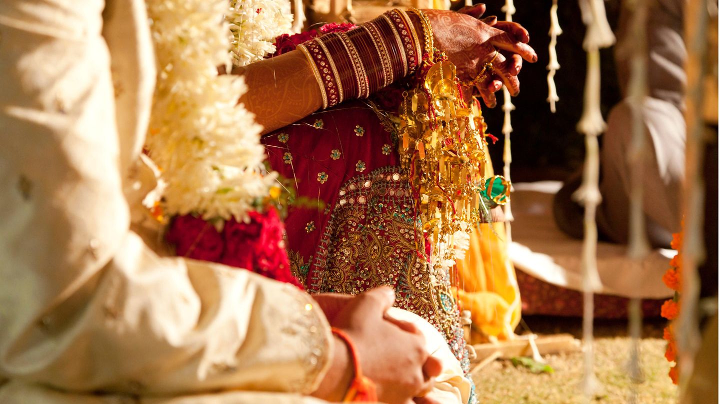 Die Hände eines indischen Paars in Hochzeitskleidung