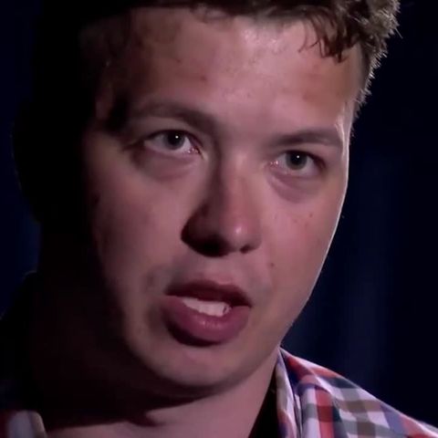 Vor einem schwarzen Hintergrund ist nur das gerötete Gesicht eines jungen Mannes mit dunkelblonden Locken ausgeleuchtet