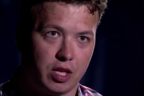 Vor einem schwarzen Hintergrund ist nur das gerötete Gesicht eines jungen Mannes mit dunkelblonden Locken ausgeleuchtet