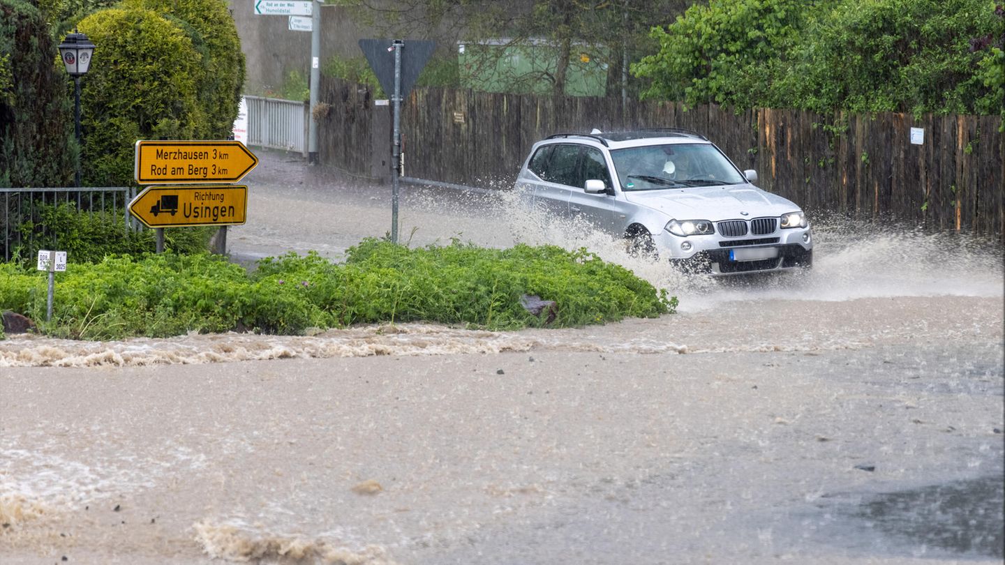 Ein Fahrzeug fährt durch eine Straße, die nach einem starken Gewitter überflutet ist