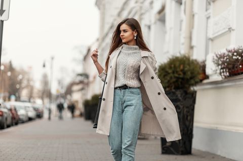 Frau auf der Straße in Mom Jeans und Trenchcoat