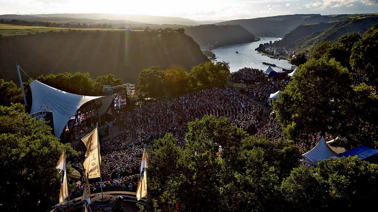 St. Goar - Ein Felsen voller Musik Zwei deutsche Mythen treffen aufeinander, und beide haben etwas mit Liedern zu tun: die Loreley, jener 132 Meter aufragende Felsen am Rhein, besungen von Heinrich Heine ("Ich weiß nicht, was soll es bedeuten"), und der Rockpalast, jene öffentlich-rechtliche Musikshow, die seit Jahrzehnten Konzerte ans Sofa liefert. In den 80er Jahren spielten auf der Freilichtbühne herausragende Künstler wie Joe Cocker, BAP, U2 und Rory Gallagher; heute noch trägt der Ort Spuren dieser Auftritte in sich. Einmal sollte man dabei gewesen sein, wenn "der Gipfel des Berges funkelt im Abendsonnenschein" (Heine), auch wenn längst nicht mehr alle Bands weltberühmt und aufregend sind.