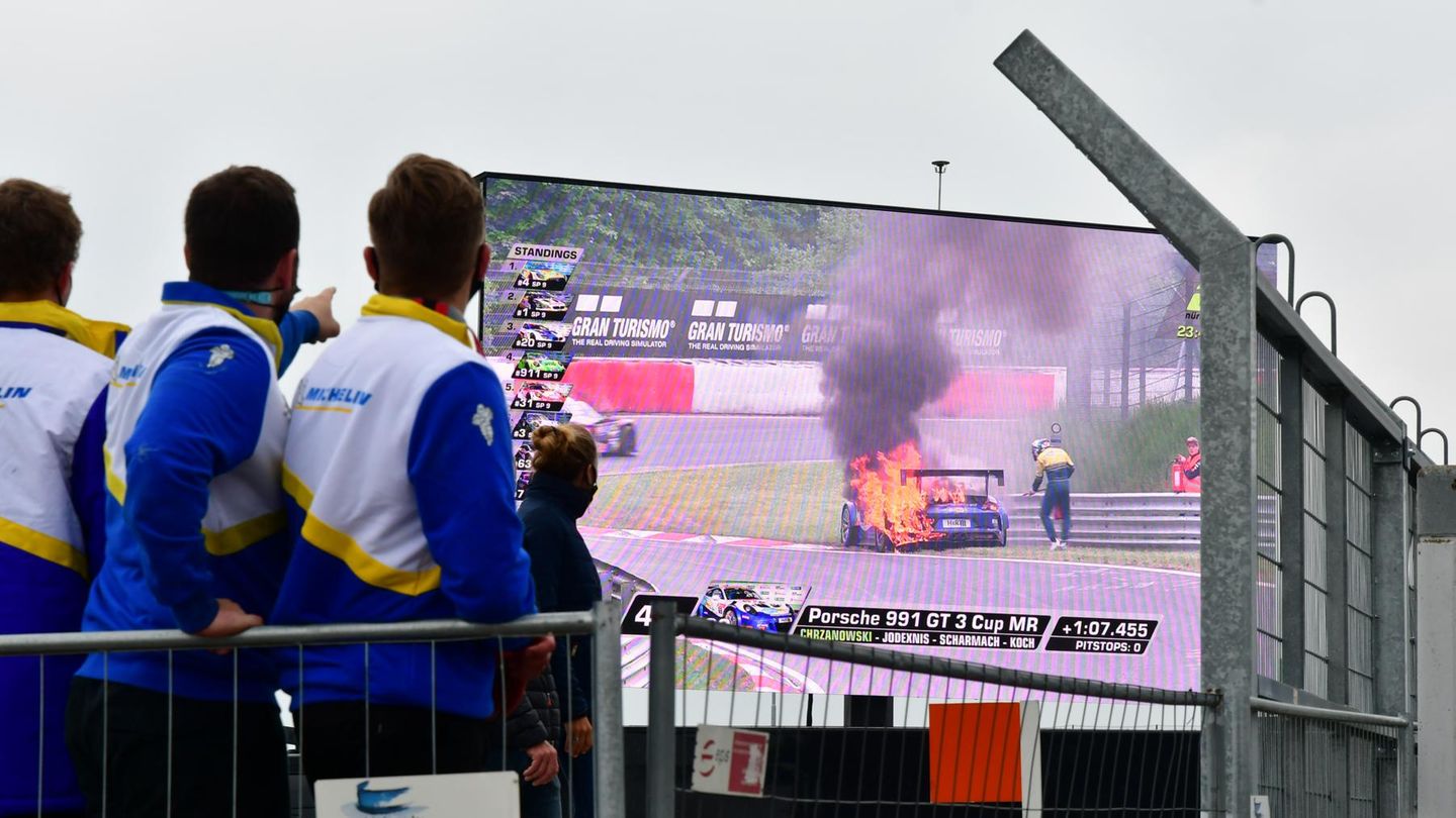 Nürburgring: Der Porsche 991 GT 3 Cup mit Startnummer 69 geht im Bereich Hatzenbach in der zweiten Rennrunde in Flammen auf. Der Startfahrer Robin Chrzanowski springt aus dem Wagen, greift sich einen Feuerlöscher und bekämpft die Flammen. Dann eilen ihm Helfer zur Seite. Die Zuschauer können das Drama auf der Fernsehtafel verfolgen. Der Porsche 991 GT 3 Cup mit Startnummer 69 geht im Bereich Hatzenbach in der zweiten Rennrunde in Flammen auf. Der Startfahrer Robin Chrzanowski springt aus dem Wagen, greift sich einen Feuerlöscher und bekämpft die Flammen. Dann eilen ihm Helfer zur Seite. Die Zuschauer können das Drama auf der Fernsehtafel verfolgen.