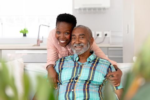 Ein Mann und eine Frau lachen Arm in Arm in die Kamera