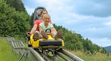 Eine Frau und ein Mädchen sausen die Sommerrodelbahn Gutach hinab