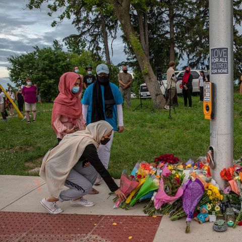 Frauen mit Hijab trauern um die Opfer eines mutmaßlich antimuslimischen Angriffs und legen Blumen an einer Ampel nieder