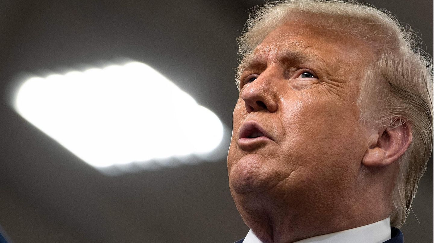 Donald Trump Trump schaut in die Höhe, neben ihm eine helle quadratische Denkenleuchte Donald Trump Trump schaut in die Höhe, neben ihm eine helle quadratische Denkenleuchte