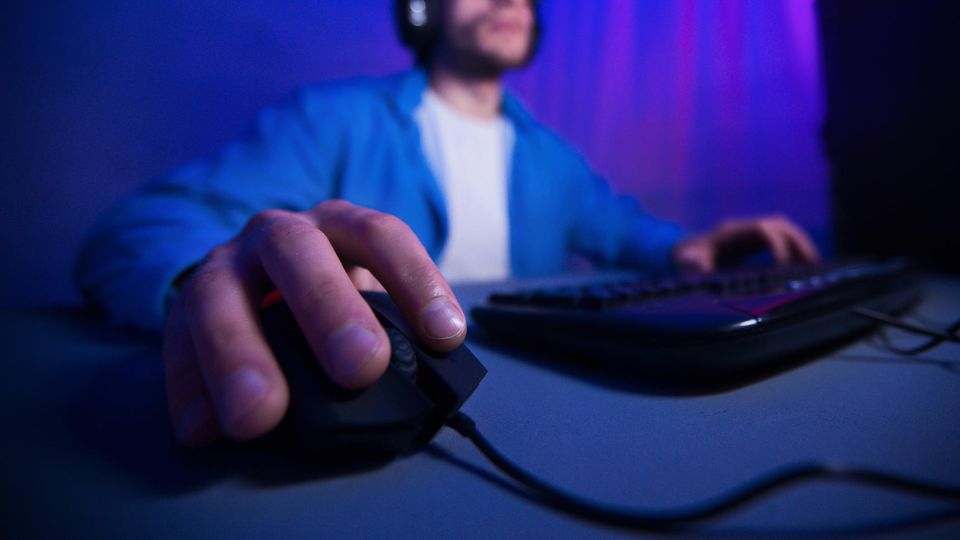 MMO-Maus: Ein Mann spielt am Computer. Mit seiner rechten Hand steuert er die Maus.