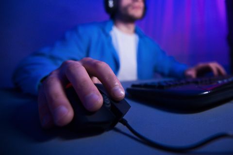 MMO-Maus: Ein Mann spielt am Computer. Mit seiner rechten Hand steuert er die Maus.