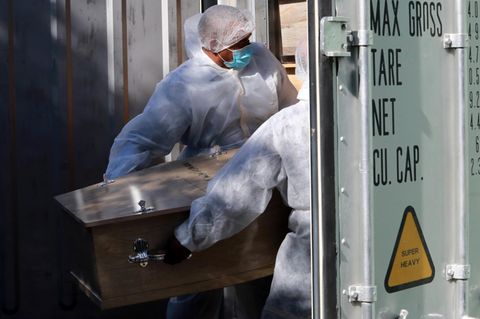 Corona-Pandemie: Bestattungsarbeiter in Kapstadt, Südafrika lagern einen Sarg in einem Kühlcontainer