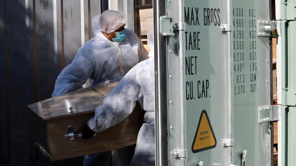 Corona-Pandemie: Bestattungsarbeiter in Kapstadt, Südafrika lagern einen Sarg in einem Kühlcontainer