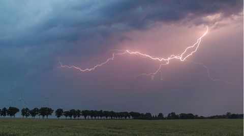 Ein Blitz erhellt den Abendhimmel über der Landschaft im Landkreis Oder-Spree. Wie ein Gewitter entsteht, erfahren Sie unten.