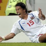 Milan Baroš sitzt auf dem Rasen, breitet die Arme aus und reißt den Mund auf