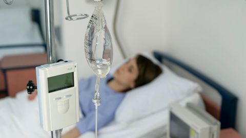 Eine Frau liegt am Tropf in einem Krankenhausbett