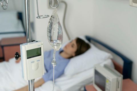 Eine Frau liegt am Tropf in einem Krankenhausbett