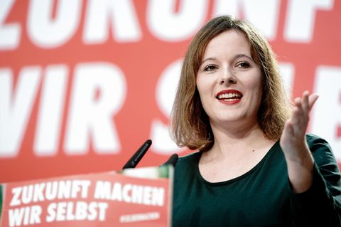 Eine junge Frau mit schulterlangen Haaren hält eine Rede vor einer roten Wand mit weißer Schrift "Zukunft machen wir selbst"