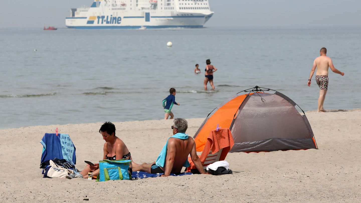 Menschen genießen den Ostseestrand, im Hintergrund ein Schiff der TT-Linie
