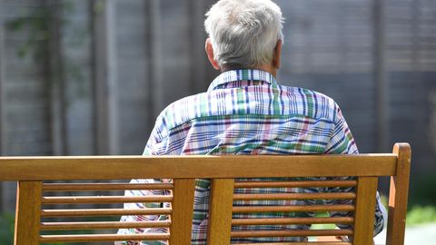 Ein älterer Mann sitzt auf einer Bank