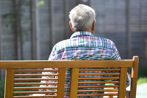 Ein älterer Mann sitzt auf einer Bank