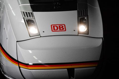 Die weiße Lok eines ICE 4 steht mit rotem "DB"-Logo zwischen den angeschalteten Scheinwerfern in einem Bahnhof